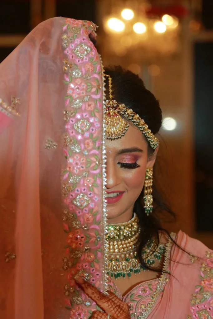 floral embroidered pink bridal veil with bride in heavy jewellery and makeup