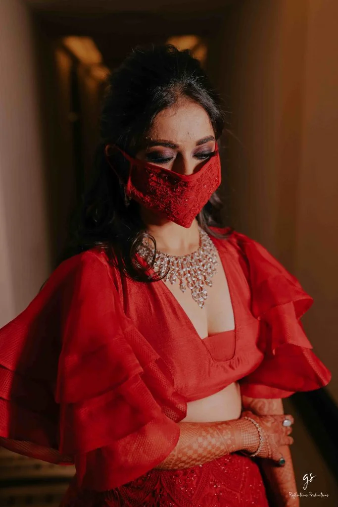 red embroidered face mask coordinating with bride's lehenga and ruffle blouse