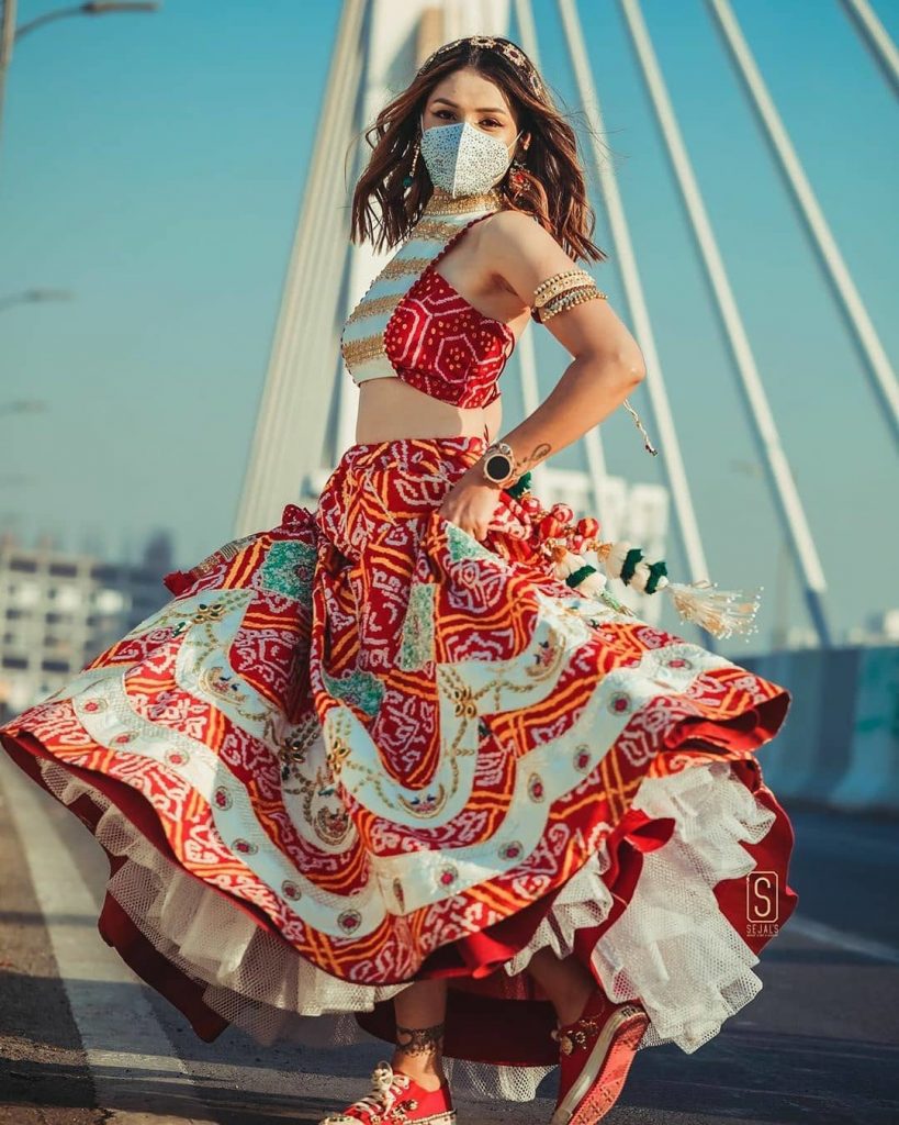 bride twirling with offbeat lehenga, red sneakers and white sequin dotted face mask