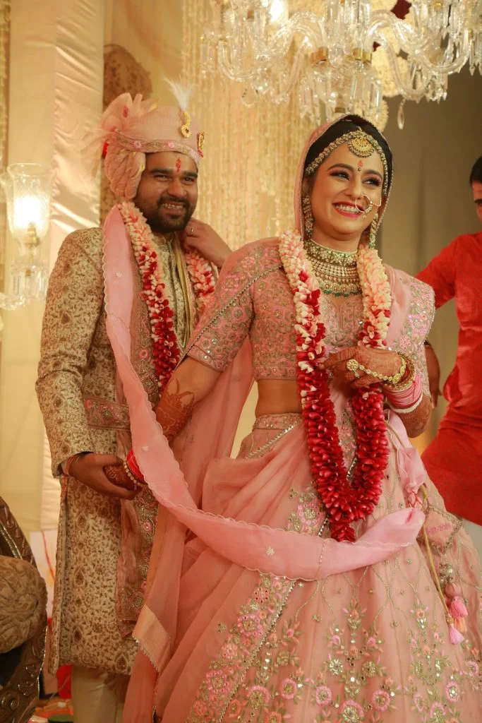 bride and groom in matching light pink attire during phera ceremony