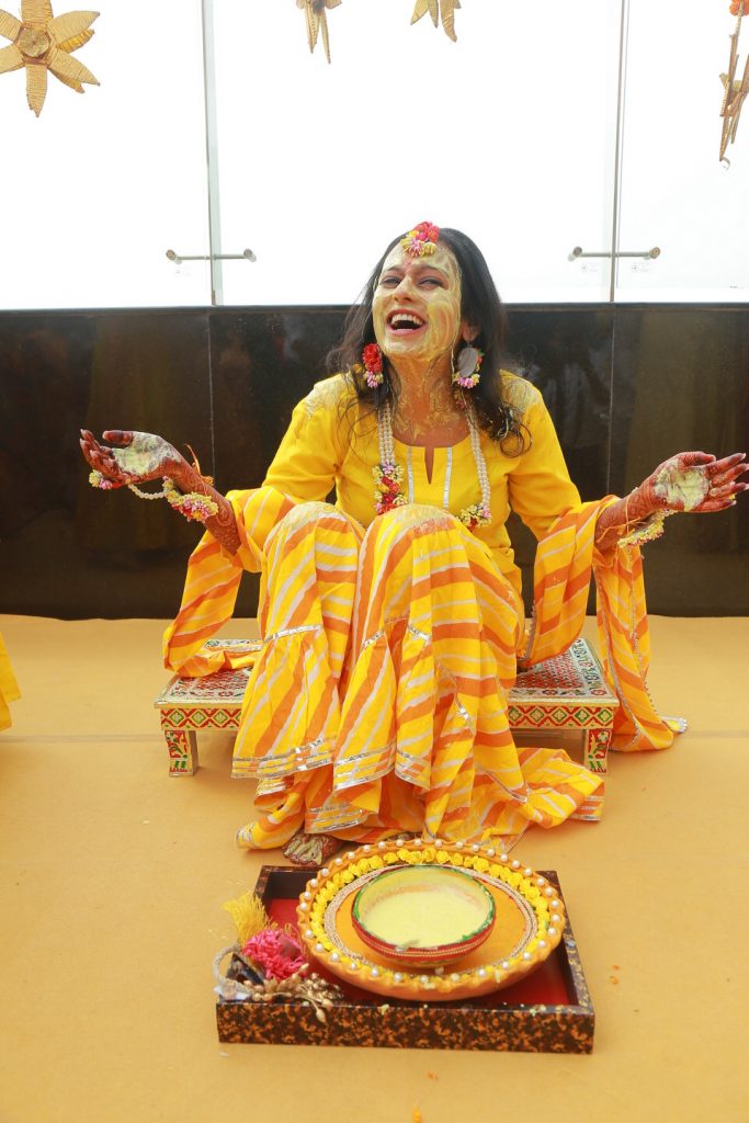 bride in yellow kurta and simple colourful flower jewellery for haldi