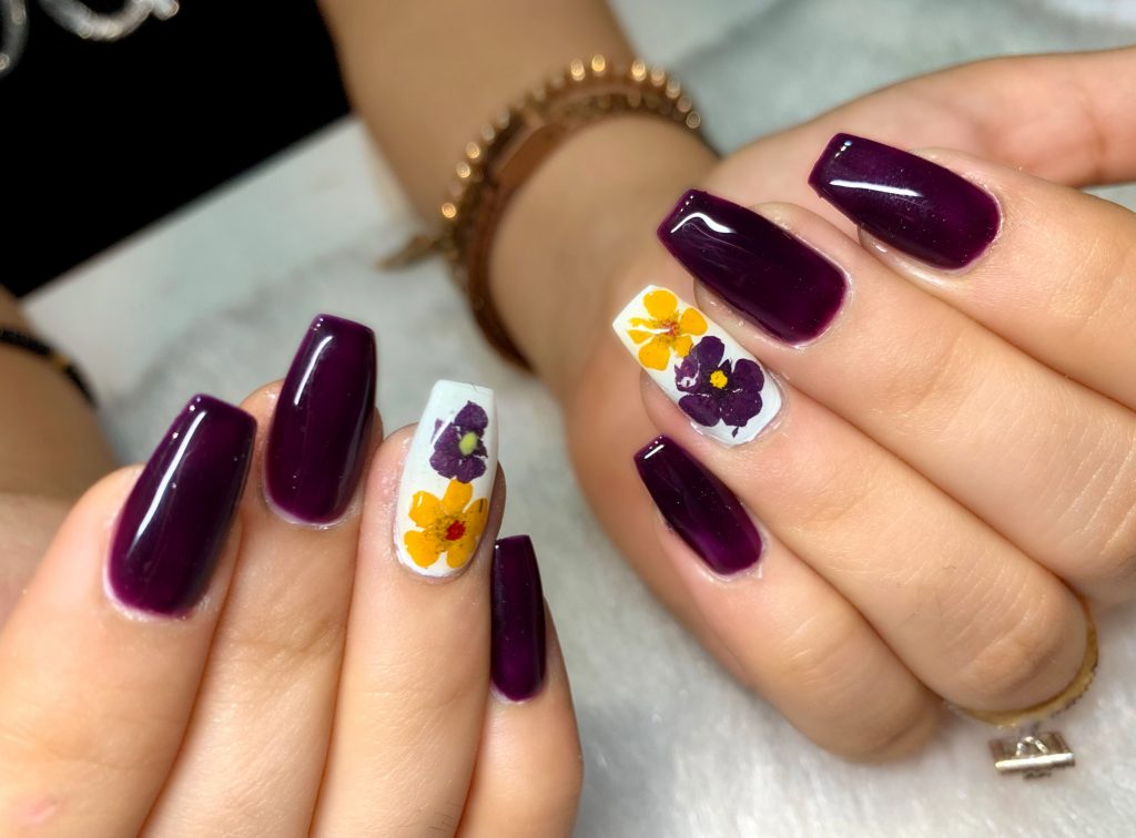 dark purple bold nails with white nails and yellow purple flower print