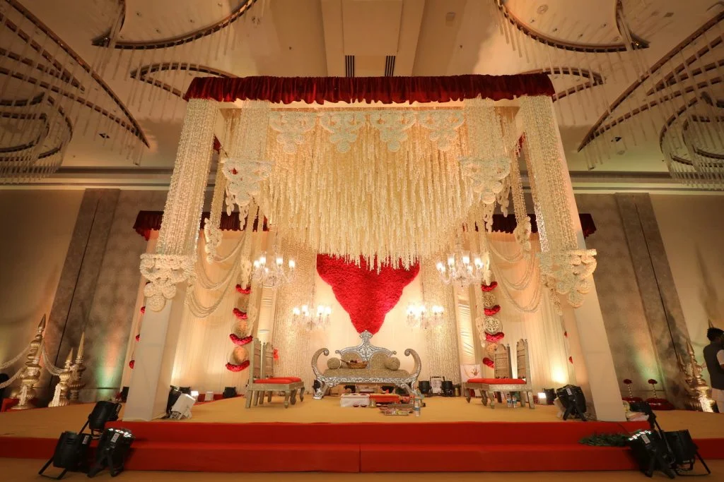 indian wedding mandap with red drapes and white floral mandap