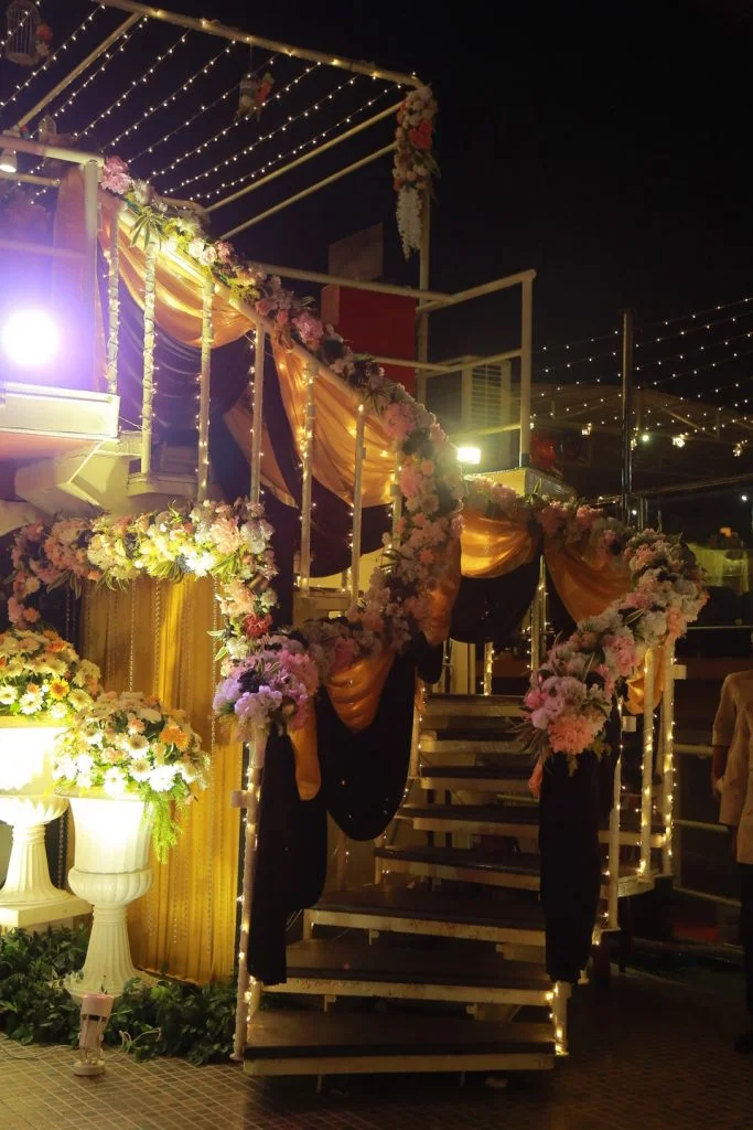 white flowers and golden red drapes on staircase for sangeet