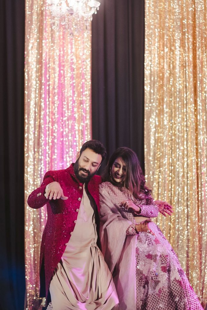 fun couple dancing in musical sangeet in coordinated outfits