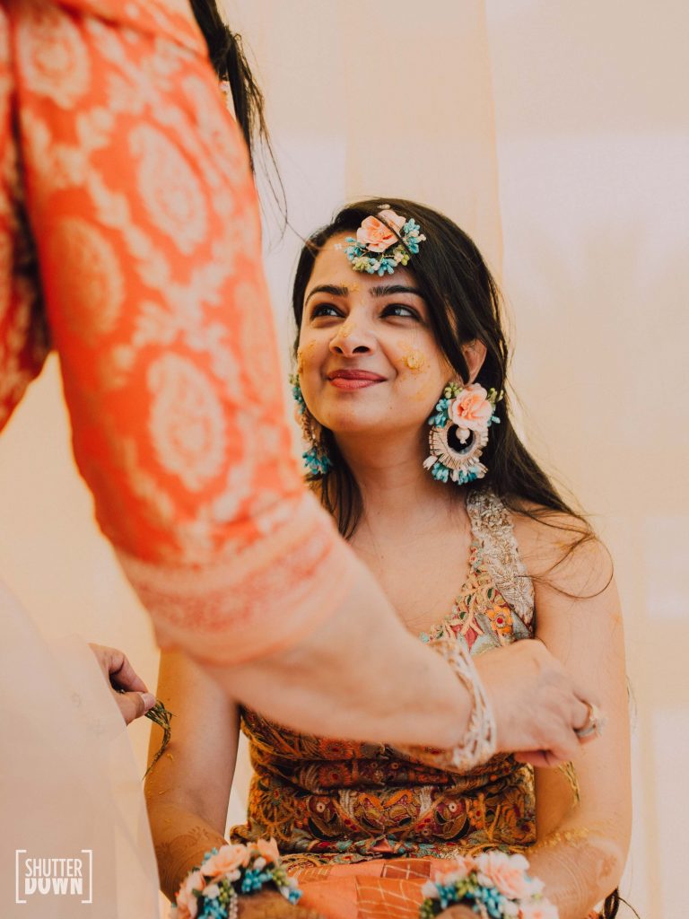 Candid Portrait of Mrighna in shades of sunrise themed haldi ceremony for her beach wedding in Dubai