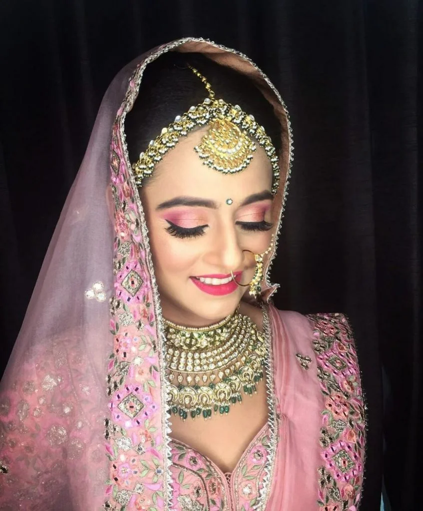 indian bride in onion pink lehenga, light makeup and golden green jewellery