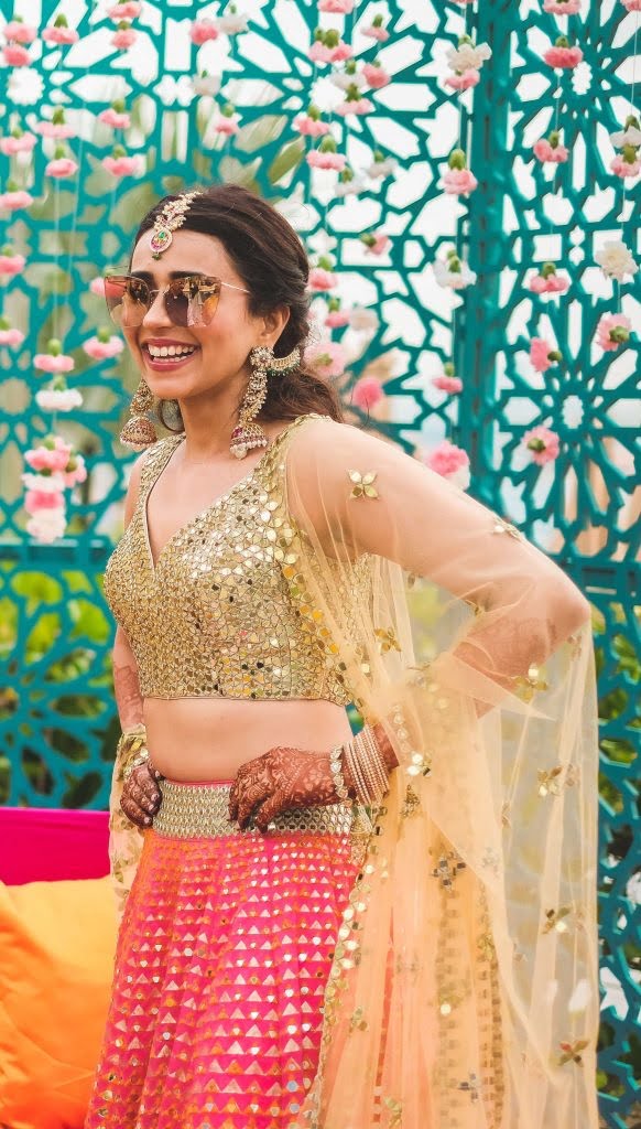 This bride curated her mehendi look by teaming a mirror work lehenga blouse and contrast skirt. 