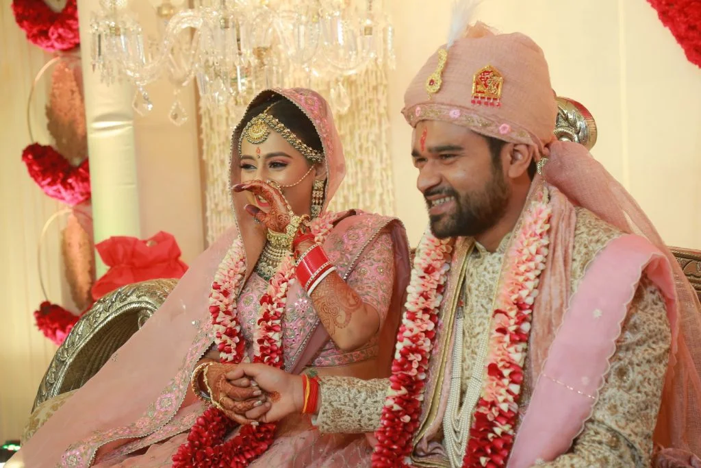candid portrait of bride in coordinated pink lehenga and groom in pink sehra