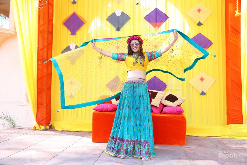 bride posing in front of kite decor haldi backdrop