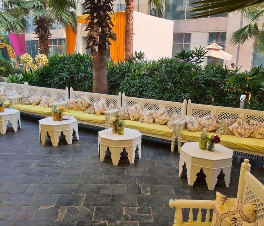 white table and sofa with white pillows and floral centerpiece for haldi decor of neha rohanpreet haldi 