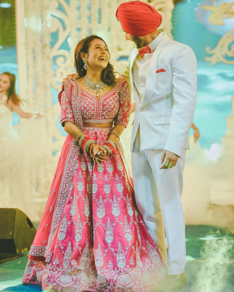 neha kakkar wearing hot pink silver embroidered anita dongre lehenga posing with rohanpreet in white tuxedo by TISA studio