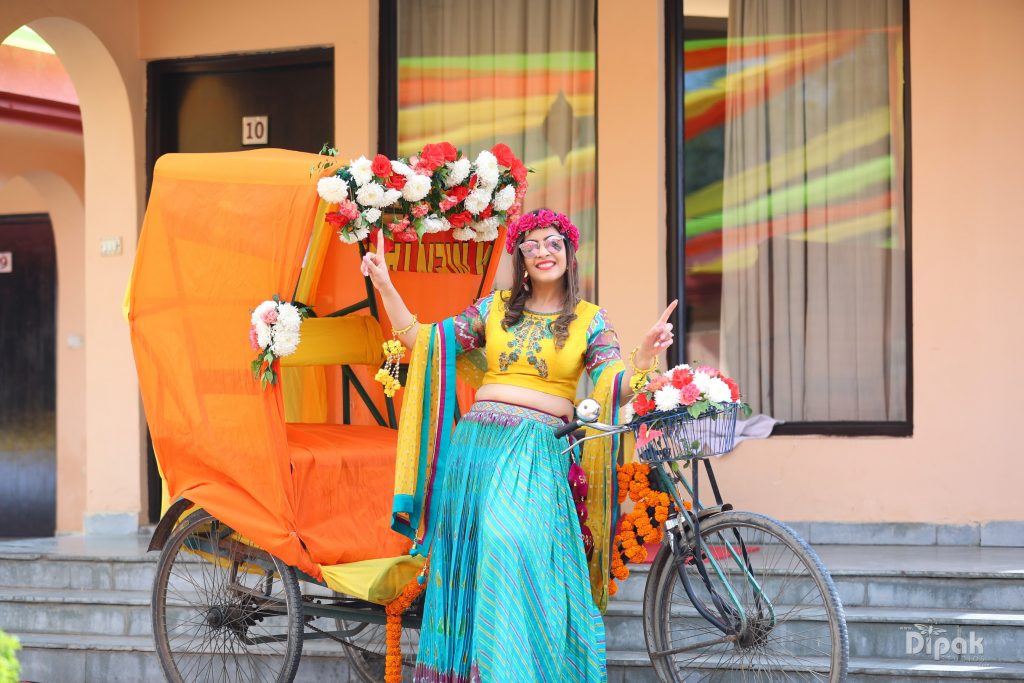 orange rickshaw with pastel flower decoration and posing indian bride