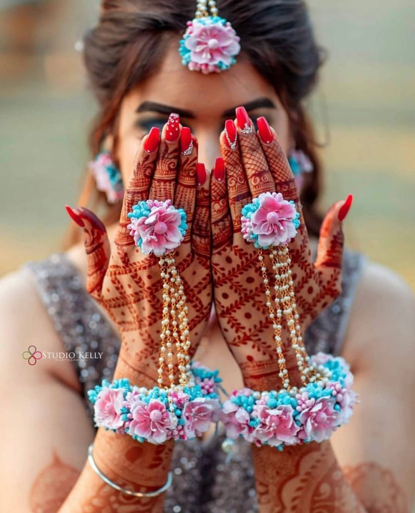 traditional red indian bridal nail art with blue pink haldi flower jewellery