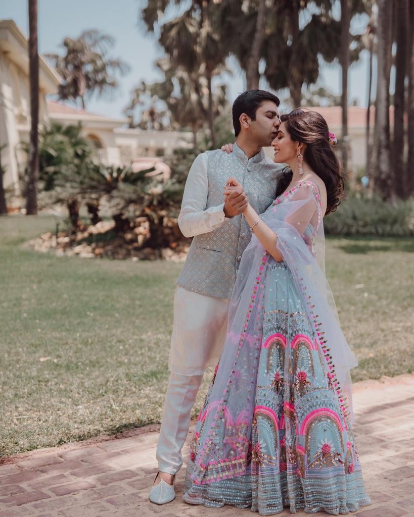 matching couple posing with pastel blue mehendi outfit for bride with pink embroidery