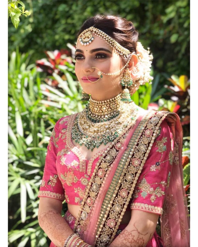 pink lehenga with green and gold jewellery