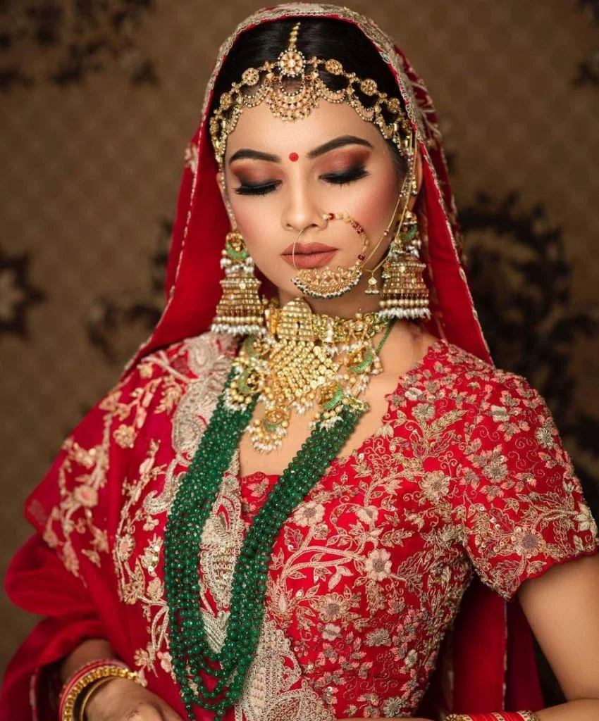 red lehenga with deep green and gold jewellery