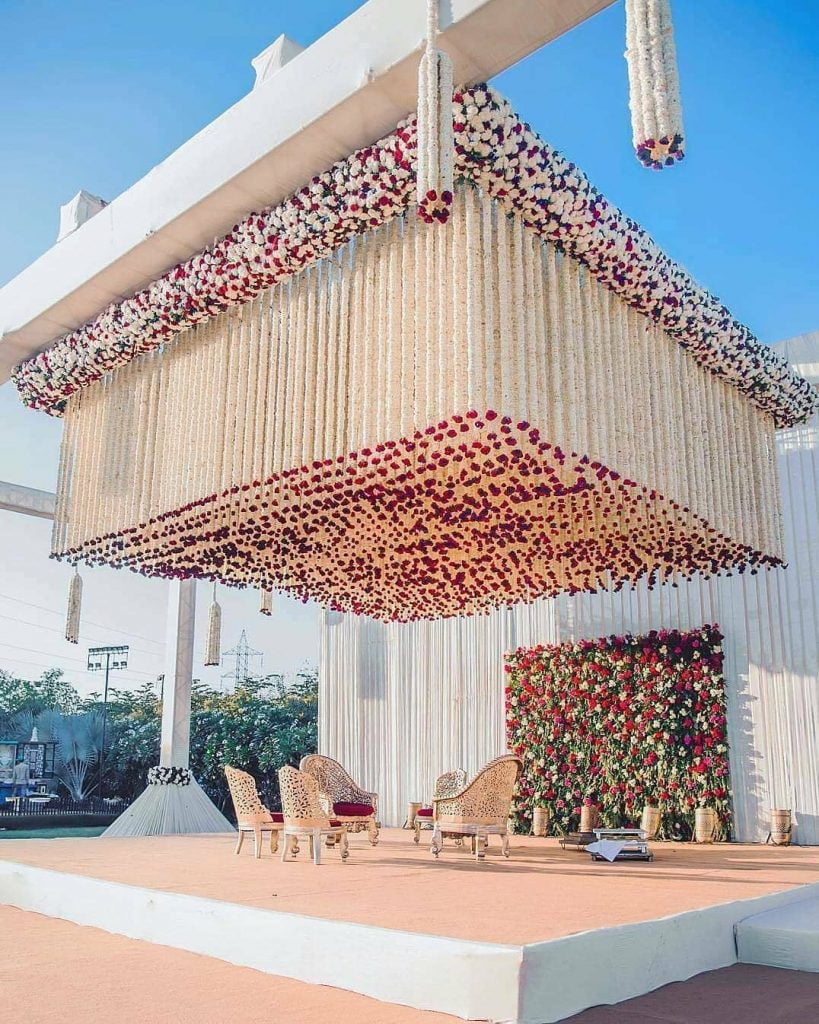 white outdoor mandap with maroon and white flowers