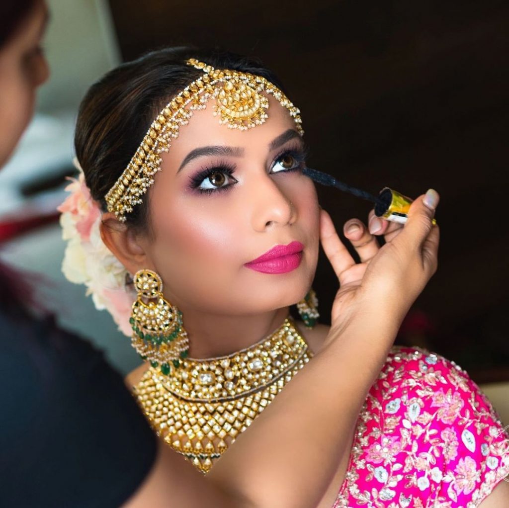 bride getting her lashes touched up with a mascara wand from her list of makeup items