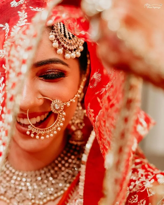Beautiful bride adorning indian bridal jewellery in a red lehenga