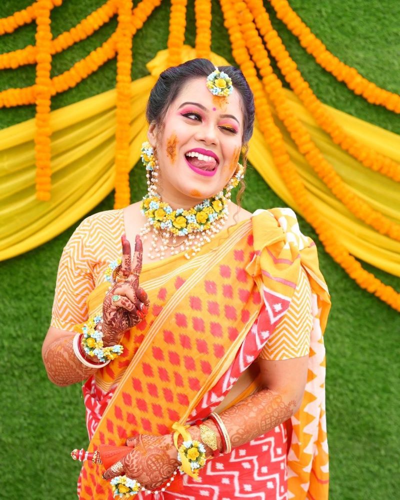 Portrait of an Indian bride sitting on stage and posing in front of camera  on haldi ceremony - SuperStock