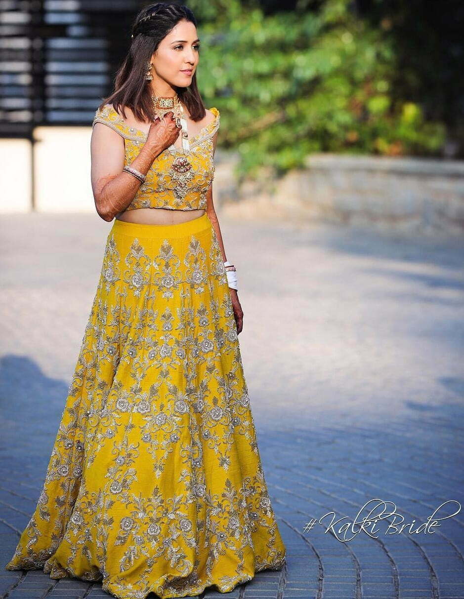 bride wearing yellow off-shoulder choli and matching lehenga on haldi