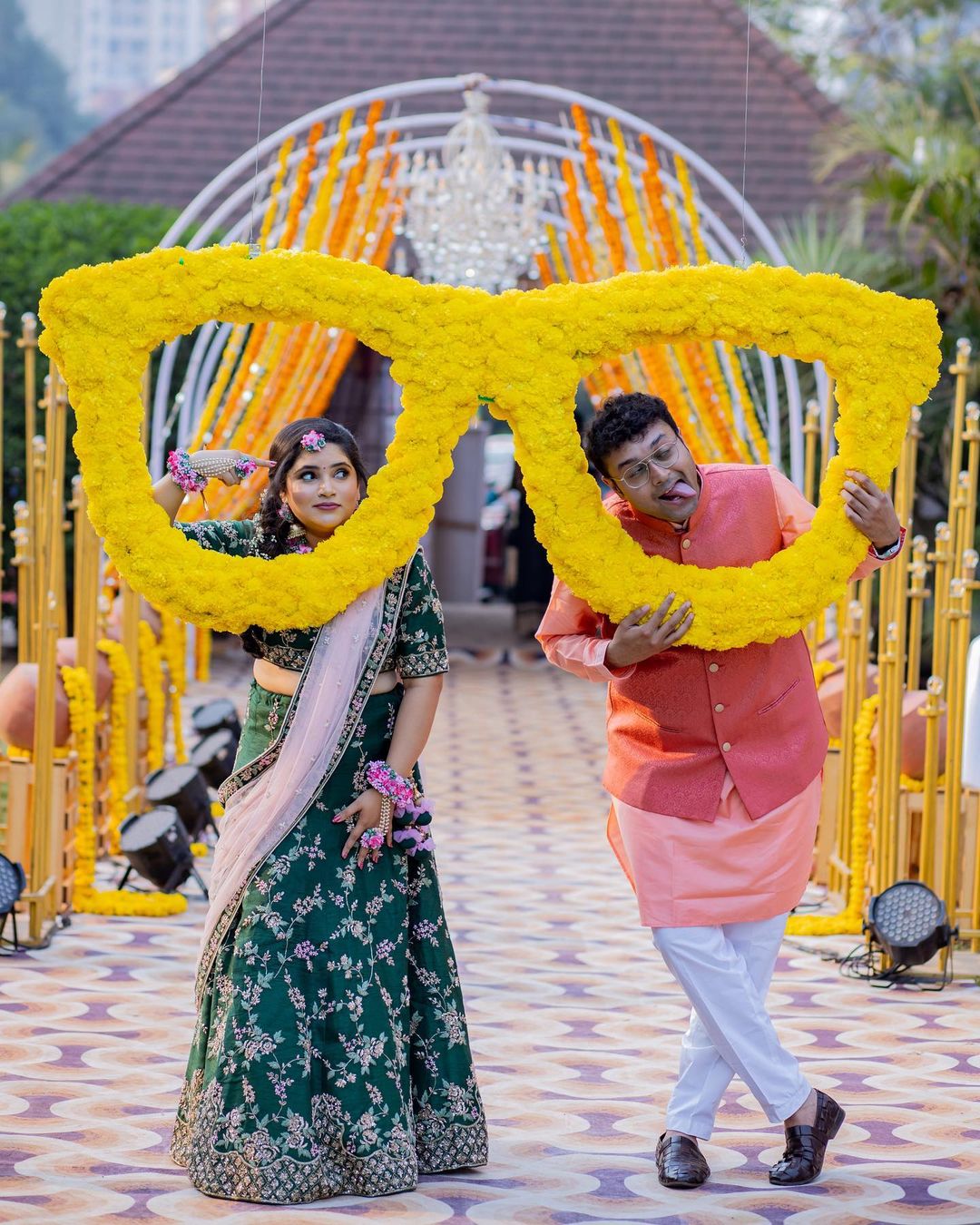 couple fun haldi poses for bride and groom with sunglasses backdrop
