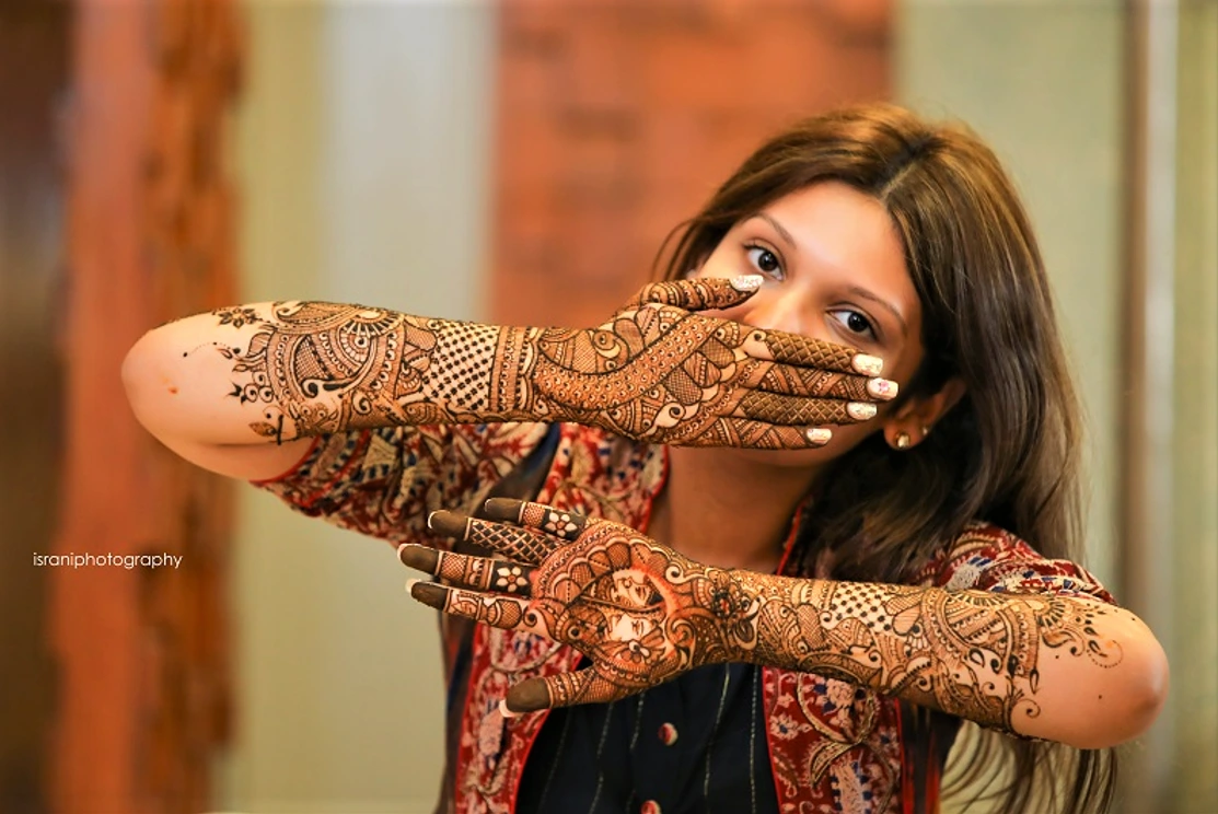 bride covering her face with mehndi laden hands