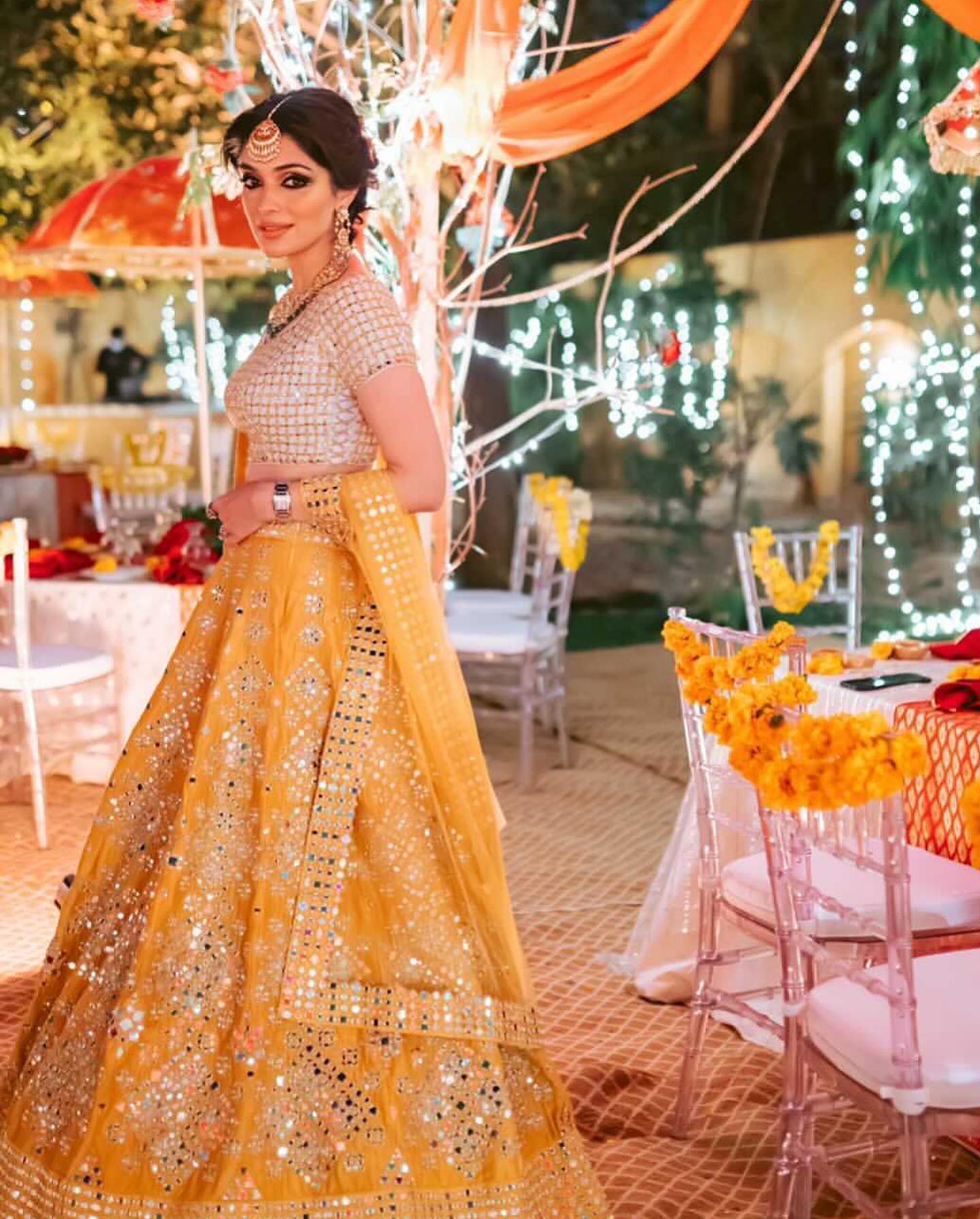 haldi look for bride in white and yellow mirror lehenga and bun hairstyle