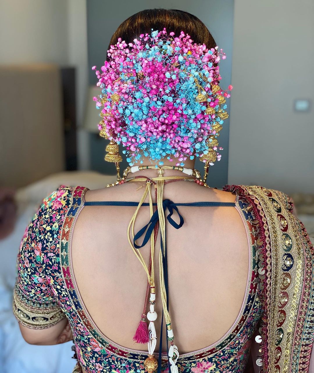 colourful floral bun hairstyle for bride on saree