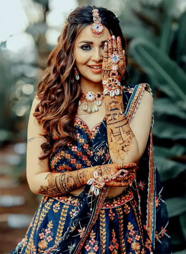 Photo of Bride posing with her mother and sister on her Mehndi ceremony.