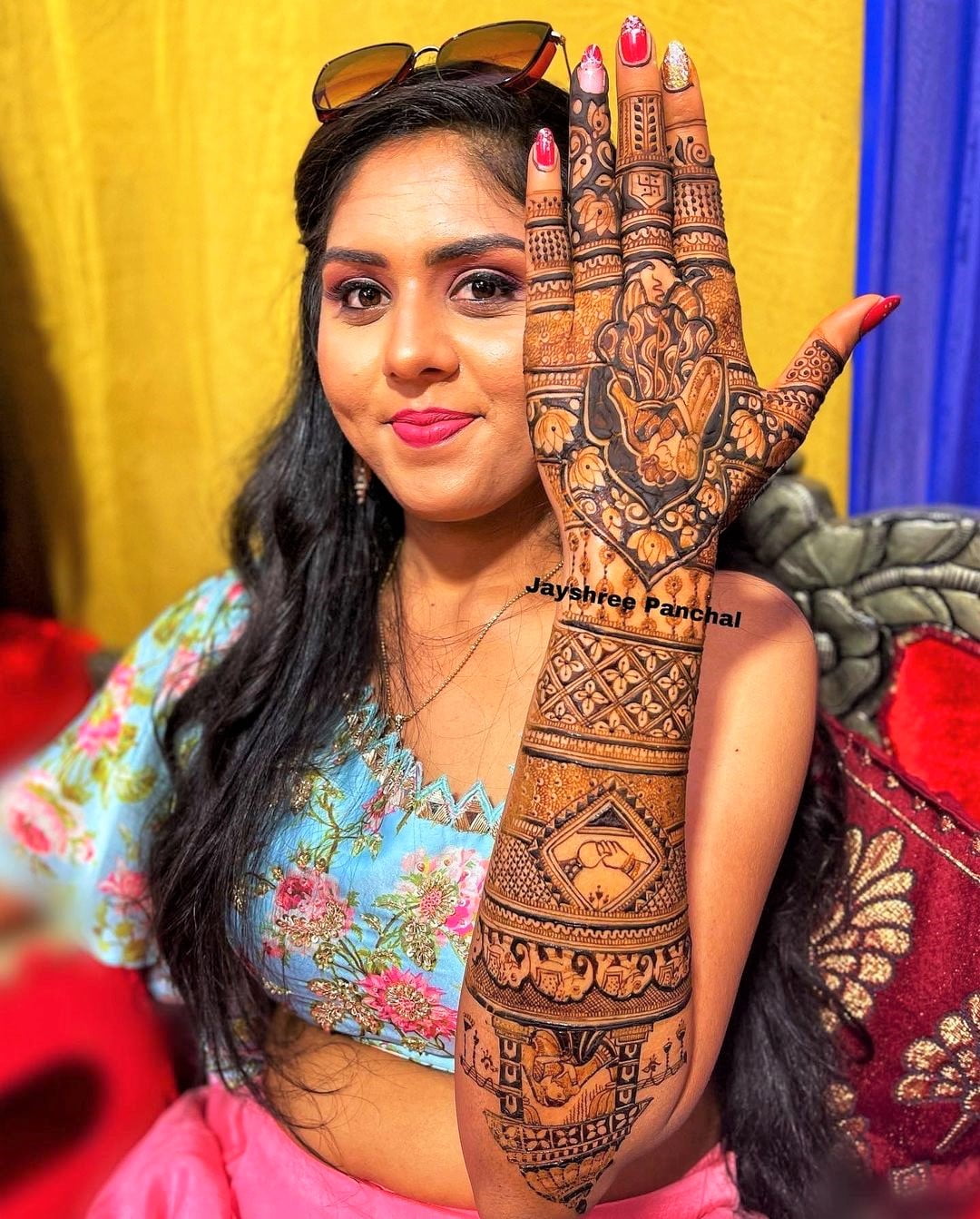 bride showing her backhand mehndi featuring doli and couple design