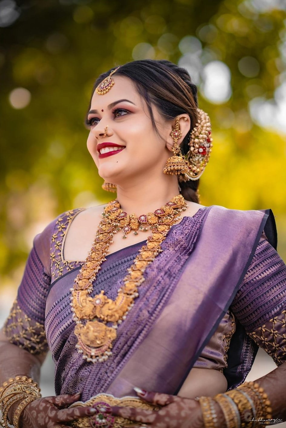 south indian bride wearing purple silk saree and gold jewellery 