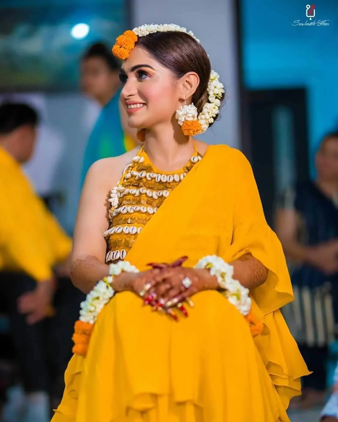 bride on her haldi in a yellow saree with shell blouse